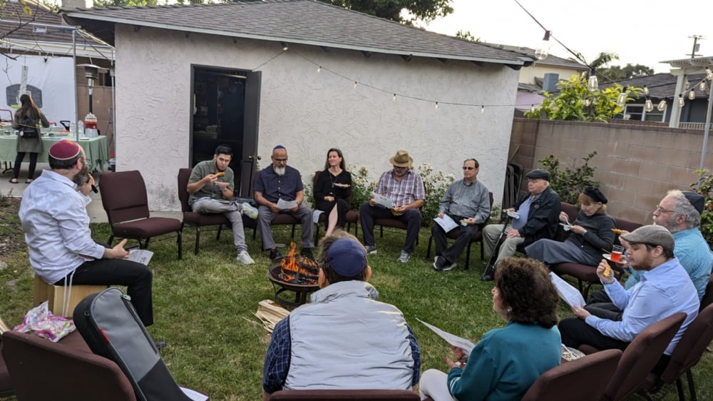 Community members sitting in a circle around the Lag B'Omer bonfire
